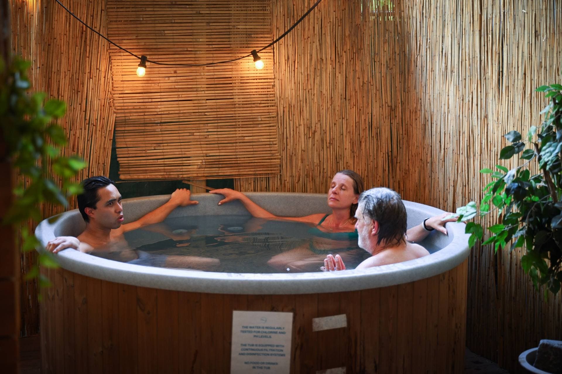 Guests relaxing in the tub under string lights in København