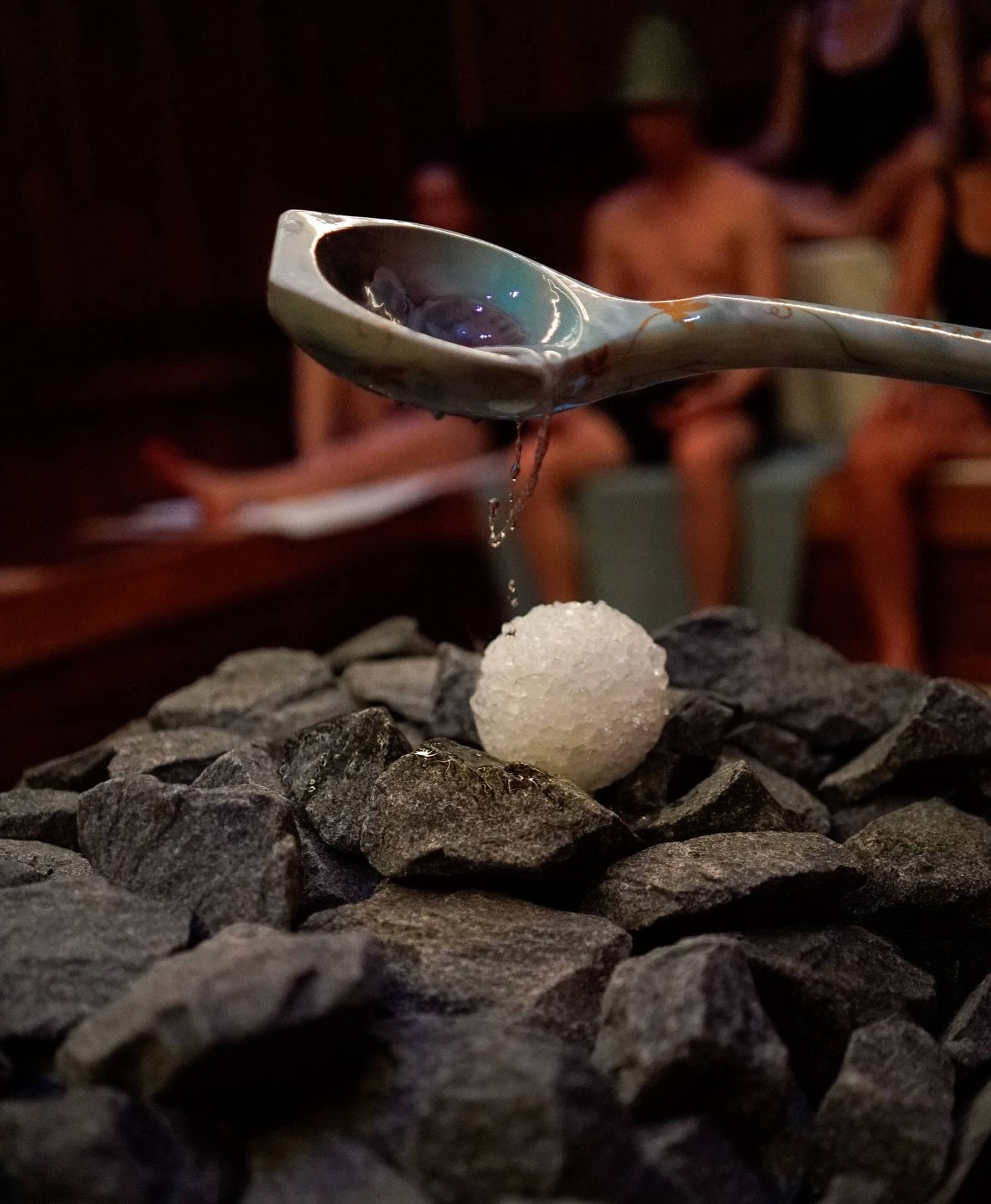 Water poured from a ladle onto an ice ball on the hot stones