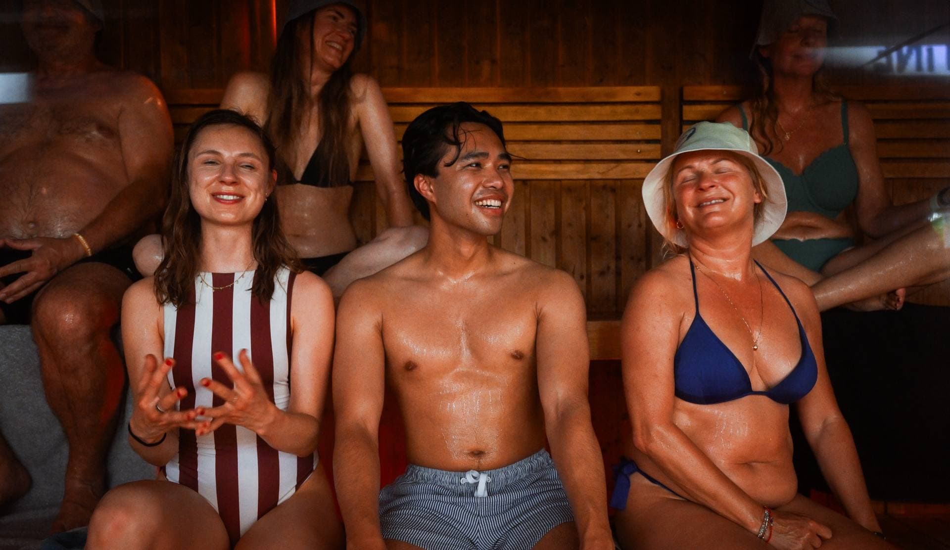 Three guests smiling on the sauna bench