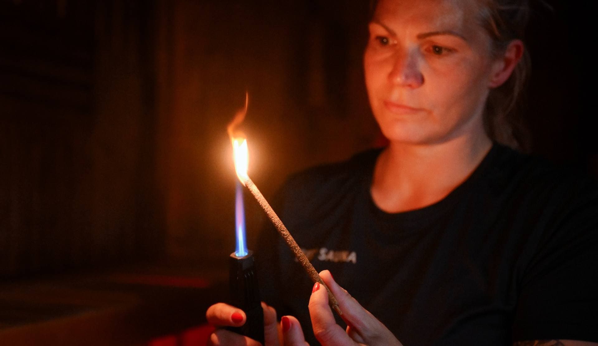 A gusmester lighting a bundle of herbs before the round