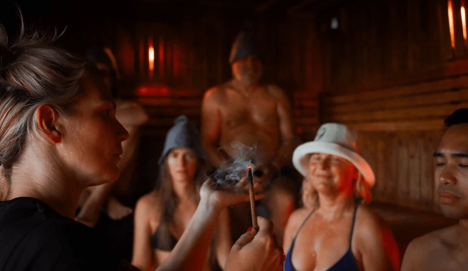 A gusmester holding incense in front of guests on the bench